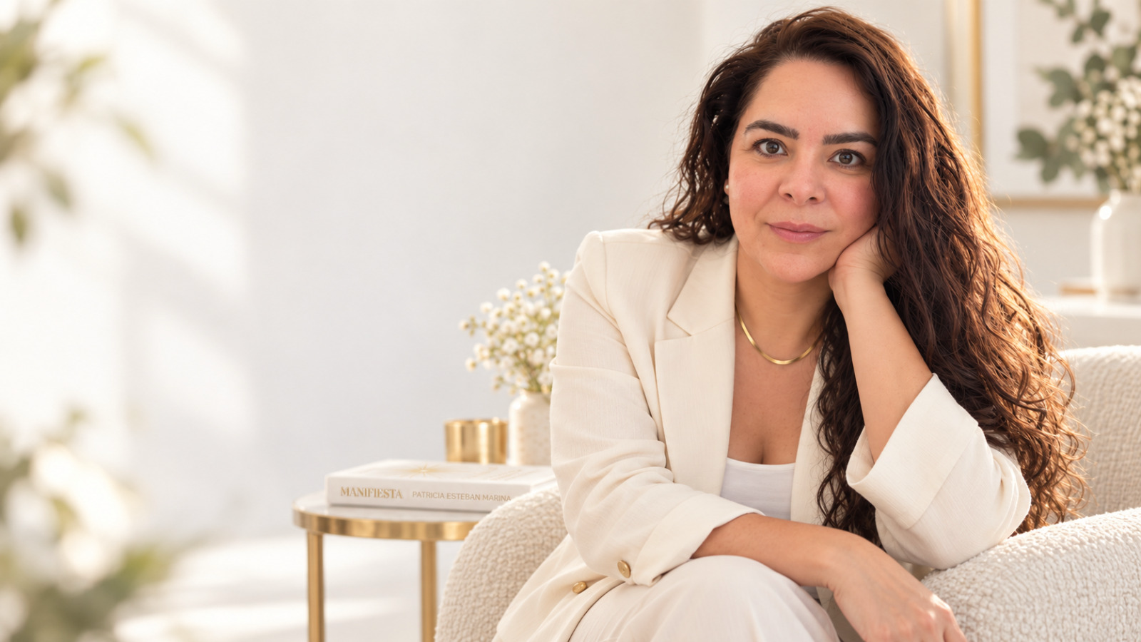 Patricia Esteban sentada en un sillón con blazer blanco